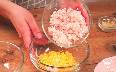 Приготовьте начинку. Вареные яйца разделите на желтки и белки. Желтки раскрошите, белки мелко нарежьте. Чеснок и крабовые палочки натрите на мелкой терке. Зелень измельчите. В одной миске смешайте яичные желтки и крабовые палочки. Заправьте 1 ст.л. майонеза или натурального йогурта. Тщательно перемешайте. В другой миске соедините чеснок и яичные белки. Заправьте солью и майонезом. Перемешайте продукты.