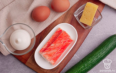 Отварите куриные яйца вкрутую и очистите. Снимите упаковку с крабовых палочек. Ополосните огурец. Сыр для блюда вы можете взять любой по вашему вкусу: российский, костромской, голландский.