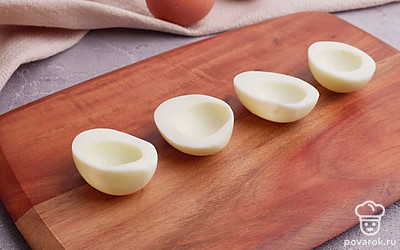 Отварные куриные яйца разрежьте вдоль пополам. Отделите желтки от белков. Белки отложите пока в сторону, желтки разомните вилкой.