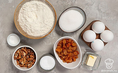 При необходимости очистите грецкие орехи от скорлупы и перегородок. Затем промойте их. Вымойте изюм, замочите его в кипятке на 10 минут, а затем обсушите. Просейте муку. Помойте яйца. Подготовьте миксер и форму для запекания. Разогрейте духовку до 180℃.