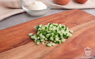 Нарежьте крабовые палочки и огурец мелкими кубиками.