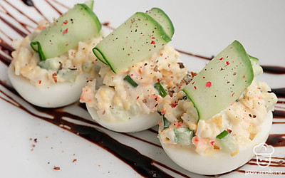 Выложите начинку в половинки яичных белков. С помощью овощечистки сделайте несколько длинных слайсов огурца и скрутите их в трубочки. Выложите огуречные трубочки сверху на фаршированные яйца. Подайте блюдо, украсив бальзамическим кремом и свежемолотым черным перцем. Приятного аппетита!