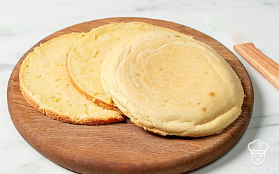 Застелите форму листом пергамента. Выложите на него тесто и разровняйте его лопаткой. Уберите форму в духовку и оставьте тесто выпекаться 35 минут при 180°C. Готовый бисквит остудите и разрежьте на 3 равных коржа.