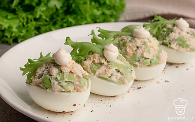 Наполните получившейся начинкой половинки яичных белков. Выложите фаршированные яйца на тарелку, украсьте салатными листьями и капельками майонеза. Посыпьте закуску свежемолотым черным перцем. Готово. Приятного аппетита!