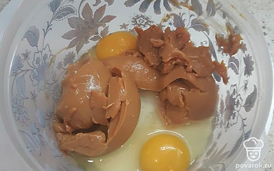 Готовим тесто для коржей. В чашу вбиваем яйца и кладем вареную сгущенку. Взбиваем.