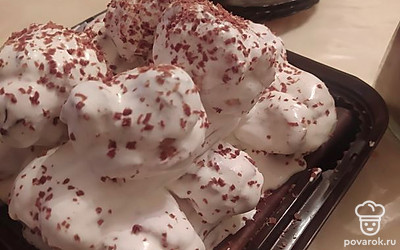 Взять три длинных эклера и промазать их кремом снаружи, опуская в крем или нанося его кисточкой. Выложить вплотную друг к другу на тарелку. После взять еще три эклера и, промазав их как и предыдущие кремом, уложить вторым слоем поперек первых трех эклеров. Взять оставшиеся длинные эклеры и, смазав кремом, выложить третьим рядом в одном направлении с первыми. Оставшиеся шарики смазать кремом и выложить наверх. По желанию украсить сверху шоколадной крошкой.