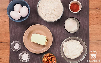 Разложите удобно все продукты. Подготовьте глубокую миску, противень, бумагу для выпекания, скалку, пищевую пленку, венчик или миксер. Заранее просейте муку через сито, чтобы насытить ее кислородом и сделать более воздушной. Размягчите сливочное масло. Грецкие орехи помойте и просушите в микроволновке или на плите.