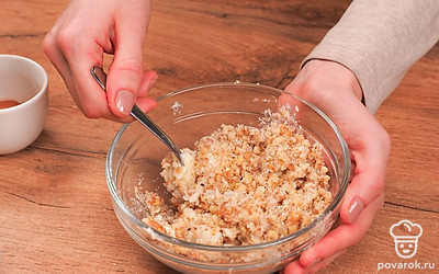 Пока тесто отдыхает, приготовьте начинку. Грецкие орехи измельчите ножом или скалкой. Переложите их в миску и добавьте размягченное масло и сахар. Перетрите содержимое до однородности.