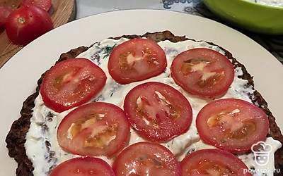 Начинаем собирать торт. На нижний слой кабачкового блина выкладываем ложку соуса. Выравниваем его и выстилаем кружочки помидора.