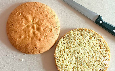 Готовый бисквит заворачиваем в пищевую пленку и отправляем на пару часов в холодильник.
Затем достаем и разрезаем корж пополам.