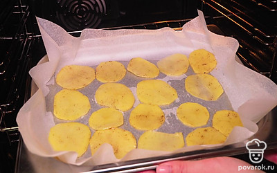 Приготовьте чипсы. Застелите противень бумагой для выпечки, чтобы картофель не прилип. Разложите каждый кусочек картофеля отдельно на небольшом расстоянии друг от друга. Запеките чипсы 10-15 минут при температуре 200℃.