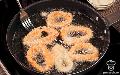 Обжарьте кольца кальмаров. Налейте растительное масло в глубокую сковороду на три пальца. Раскалите масло на среднем огне. Кольца обмакните в кляр, а затем обваляйте в сухарях. Выложите несколько таких колец в горячее масло. Обжарьте примерно в течение 2 минут. Не передерживайте, иначе кальмар будет очень жестким. Хрустящие колечки выложите на бумажную салфетку, чтобы убрать из них лишний жир.