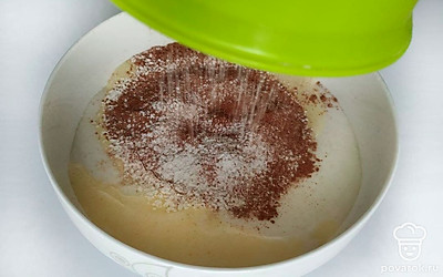 Приготовьте тесто для коржей: отделите желтки от белков и взбейте их до пиков с половиной сахара. Остальной сахар и желтки тоже взбейте отдельно. В конце взбивания добавьте воду. Осторожно соедините взбитые белки и желтки. Просейте к полученной яичной массе муку, какао и разрыхлитель. Аккуратно перемешайте.