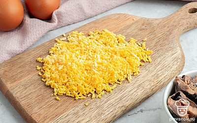 Вареные яйца очистите от скорлупы, разрежьте пополам и извлеките желтки. Натрите их на мелкой терке.