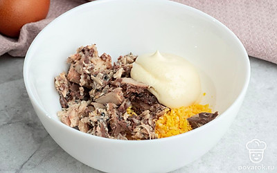 В подходящую емкость выложите желтки и размятые рыбные консервы. Посолите на свой вкус, добавьте майонез и смешайте до однородности.