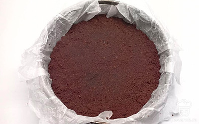 Утрамбуйте бисквитные крошки в форму, застеленную пергаментом. Сверху выложите крем и равномерно его распределите. Уберите торт в холодильник на ночь.