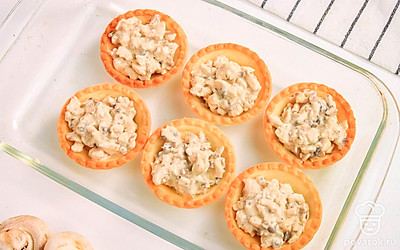 Выложите тарталетки в форму для запекания. Заполните тарталетки начинкой из курицы и грибов.