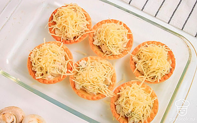 Посыпьте тарталетки тертым сыром.