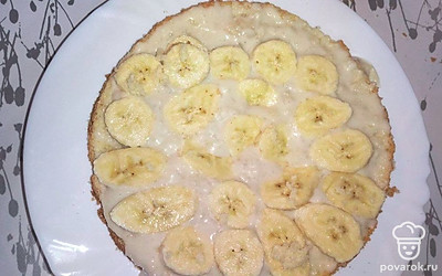 Остудите бисквит и нарежьте на две равные части. По желанию пропитайте бисквит сиропом. На нижнюю часть выложите и распределите крем, поверх выложите бананы. Накройте второй частью бисквита, полейте кремом и уберите в холодильник.