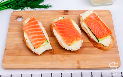 Сверху на сыр выложите огурцы, затем ломтики красной рыбы.