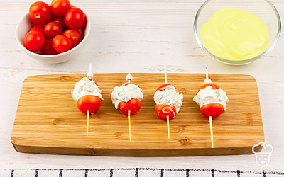 На шпажку насадите половину томата, скатайте шарик из сырной смеси и положите на черри. Сверху закрепите второй половинкой помидора.