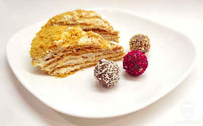 Медовый торт выньте из холодильника, нарежьте порционными кусочками. Выложите на десертную тарелку, добавьте шоколадные конфеты, подавайте с горячими напиткам.