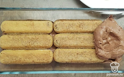 Обмакните печенье в остывший кофе на пару секунд с обеих сторон, выложите на дно формы. Сверху распределите часть крема. Повторите слои, пока не закончатся печенье и крем, так чтобы последним слоем был крем. Поставьте торт в холодильник на 10 часов.