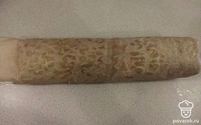 Извлеките из духовки корж и переверните на доску. Снимите бумагу, на которой он выпекался, затем верните корж обратно на бумагу и вместе с ней сверните в рулет. Оставьте его остывать.