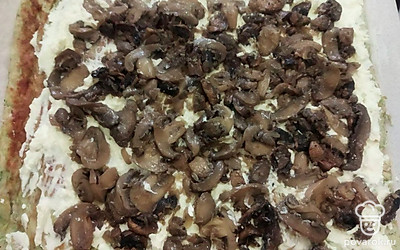 Кабачковый корж смажьте сливочным сыром. Сверху, но не до края, выложите обжаренные шампиньоны с луком. Сверните плотный рулет и заверните его в пищевую пленку. Отправьте в холодильник на пару часов.