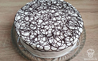 Удалите кольцо и ацетатную пленку. Обмажьте верх и бока торта остатками крема. Шоколад и кусочек сливочного масла растопите в микроволновке. Получившуюся глазурь поместите в корнетик и нанесите на торт кружевные узоры.