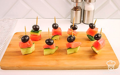 На зубочистку последовательно насаживайте маслину, семгу и кусочек огурца. Чтобы канапе было устойчивым, не протыкайте огурец насквозь - он служит основанием. Повторите процедуру для каждого бутербродика.