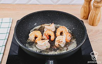 На сковороде растопите сливочное масло, выложите в нее креветки и обжаривайте на медленном огне.