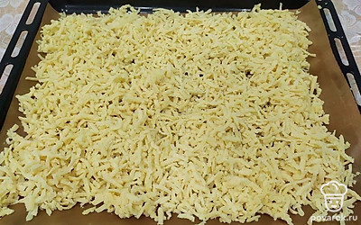 Противень выстелить пергаментной бумагой, натереть тесто на крупной терке или прокрутить через мясорубку, равномерно распределить по противню. Отправить в духовку на 180 градусов, пока крошка не приобретет золотистый цвет.