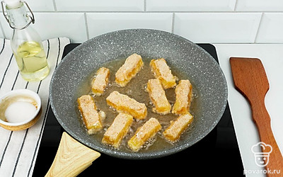 В глубокой сковороде разогрейте масло, выложите сырные брусочки и обжаривайте на огне чуть выше среднего до образования золотистой корочки.