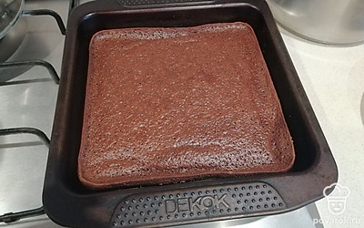 Приступите к сборке торта: сперва смажьте коричневый корж, затем кусочки белого коржа обмакните в крем и уложите в беспорядке на коричневый корж.