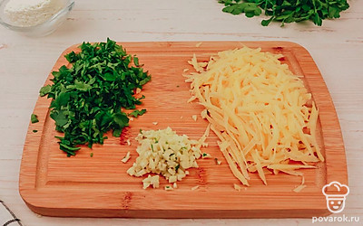В это время приготовьте начинку. Потрите сыр на крупной терке, порежьте чеснок и зелень.