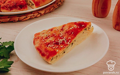 Посыпьте лепешку кунжутом, разрежьте на порции и украсьте свежей зеленью.