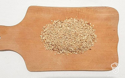 Обжарьте орехи на сковороде до легкого румянца. На разделочной доске при помощи скалки измельчите орехи в крупную крошку, или нарежьте их ножом очень мелко.