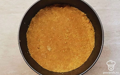 Измельченное печенье соедините с растопленным сливочным маслом. Тщательно перемешайте. Застелите дно разъемной формы пергаментом. Выложите основу для торта в форму, хорошо утрамбовав массу. Поставьте в холодильник на 30 минут.