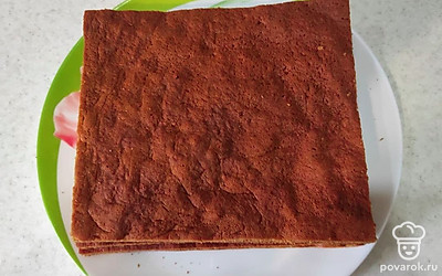 Приступите к приготовлению сметанного крема. Сметану взбейте миксером или венчиком с сахаром до однородности. Остывшие коржи сложите один на другой, обрежьте по краям, чтобы они были ровные и одинаковые. Обрезки растолочите на мелкие крошки, чтобы сделать посыпку.