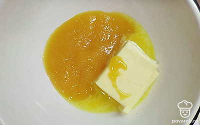 Начните готовить тесто для коржей, для этого сделайте водяную баню из двух кастрюль разного диаметра. Добавьте в меньшую кастрюлю мед и сливочное масло и поставьте ее в кастрюлю большего диаметра с водой. Включите огонь и постоянно помешивая, растопите сливочное масло и мед.