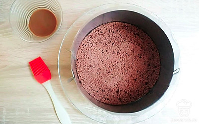 Приготовьте шоколадный бисквит. Взбейте яйца с сахаром до пышности и увеличения массы в два три раза. Постепенно добавляйте в яичную смесь муку, сахар и какао. Перемешайте. Запекайте 30 минут при температуре 180С. Первые 20 минут духовку не открывайте. Готовый бисквит остудите на решетке и обрежьте верхушку. Дно кольца для сборки торта обтяните пищевой пленкой, а бока выложите плотной пленкой. Положите в кольцо бисквит и пропитайте хорошо сиропом.