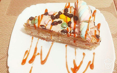 Край бисквита по периметру украсьте пастилой в виде жгута, или нанесите крем фигурной насадкой. Внутри разложите мелкие шоколадные и разноцветные драже, чтобы получился узор. Подавайте порциями, на которые нанесите карамельный рисунок.