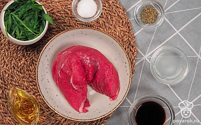 Подготовьте продукты для карпаччо. Говяжью вырезку очистите от пленок. Рукколу промойте, удалите твердые стебельки и обсушите. ½ часть Пармезана натрите на средней терке, вторую половину нарежьте слайсами с помощью овощечистки или специального ножа для сыра. Совет: Для того, чтобы выбрать говяжью вырезку хорошего качества, стоит обратить внимание на равномерный цвет по всей поверхности, отсутствие слизи, упругую структуру мяса.