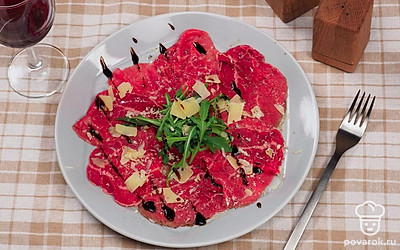 Перед подачей сбрызните тарелку бальзамическим уксусом и лимонным соком, выложите на нее кусочки мяса. Вокруг карпаччо выложите рукколу, посыпьте тертым пармезаном. По бокам разложите пармезановые слайсы. Подавайте к столу с красным вином.