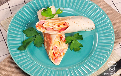 Чтобы эффектно подать жареный лаваш с колбасой и сыром, сложите его в форме небольших аккуратных треугольников. Для этого на этапе сборки закуски порежьте лаваш на полоски шириной 7-9 см, на основание каждой выложите немного начинки в форме треугольника, затем по форме начинки складывайте лаваш в треугольник.