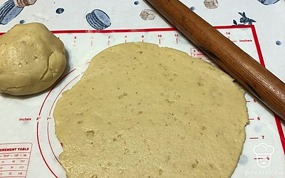 Тесто достаньте, разделите его на 2 части. Одну раскатайте в пласт. Измельченные орехи хорошо распределяются.