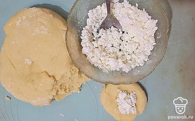 Творог смешайте с сахарной пудрой. Скатайте из теста шарик, прижмите его его, в середину выложите немного творога.