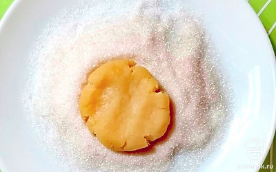 Положите шары по очереди в тарелку с сахаром. Придавите, делая лепешку толщиной в 1 сантиметр.