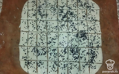 Раскатайте тесто в пласт толщиной примерно 1 сантиметр. Посыпьте 1 столовой ложкой сахара и кунжута. Разрежьте на квадратики. Отправляем в разогретую духовку при температуре 180 градусов на 15 минут.